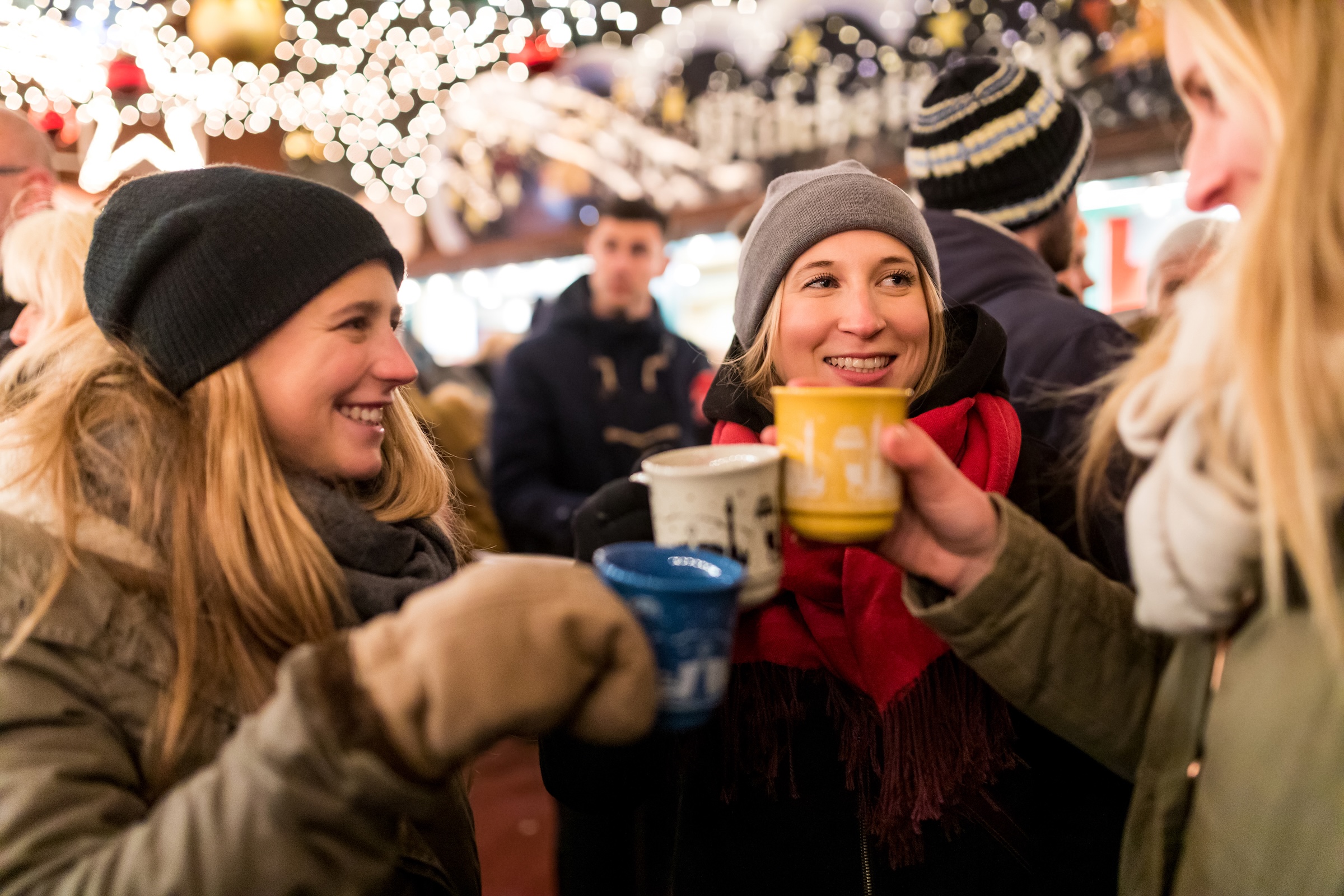 Drei Frauen sto&szlig;en auf einem Weihnachtsmarkt an.
